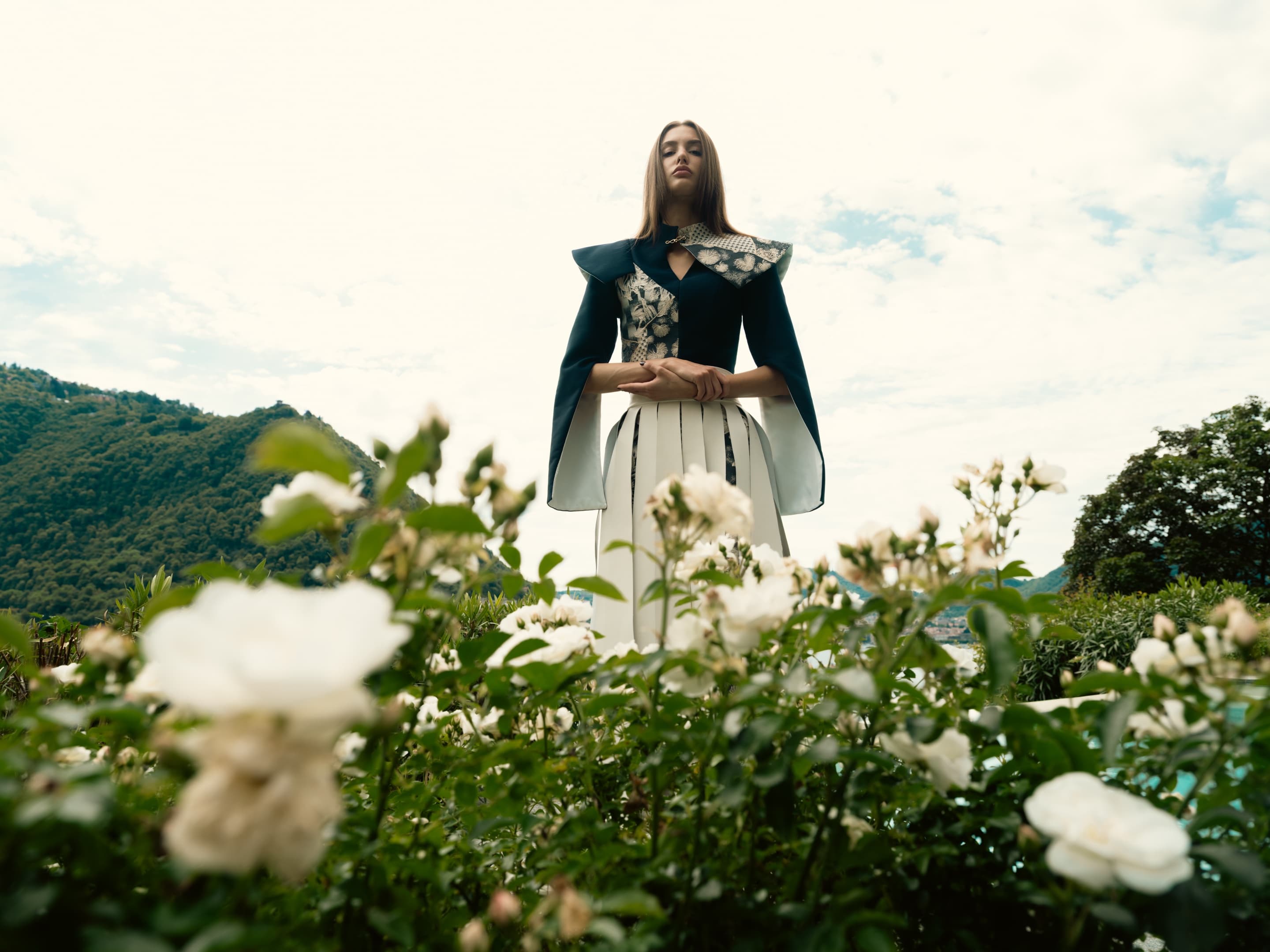 Model standing in white roses with Como mountains behind